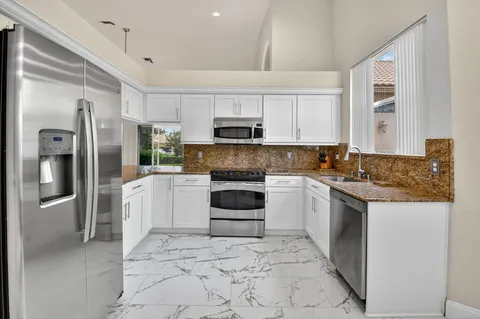 a kitchen with stainless steel appliances granite countertop a refrigerator a stove and a sink