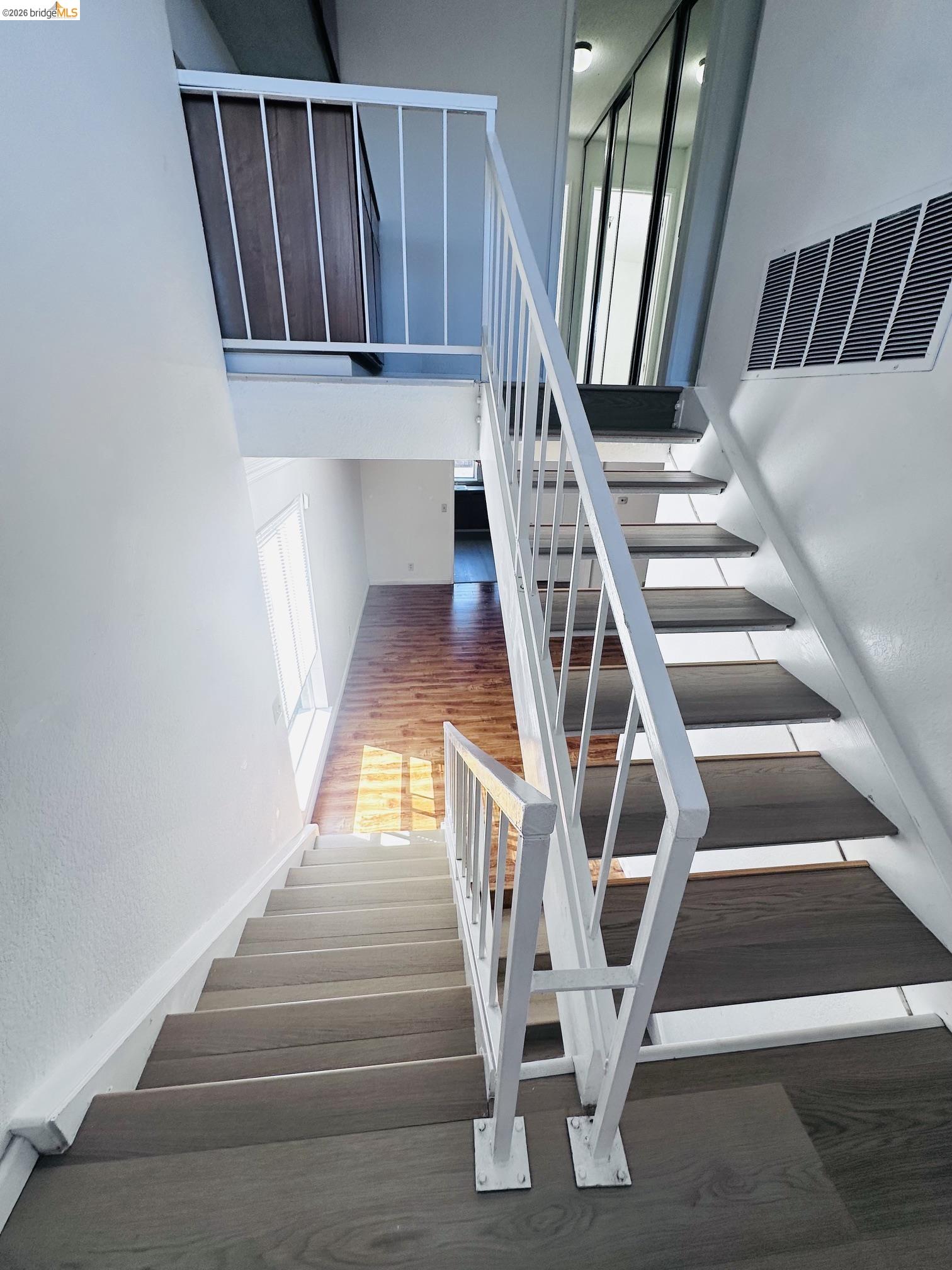 2121 Vale Road, Unit 50 San Pablo, CA 94806 - Photo 14 of 26 Split-level interior featuring modern white railings, wood-finish flooring, and a second-level balcony with wood-panel detailing