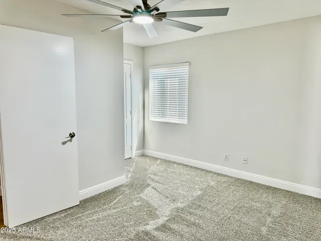 an empty room with a ceiling fan and a window