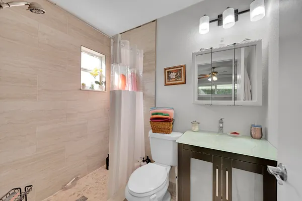 a bathroom with a granite countertop sink a toilet a mirror and shower