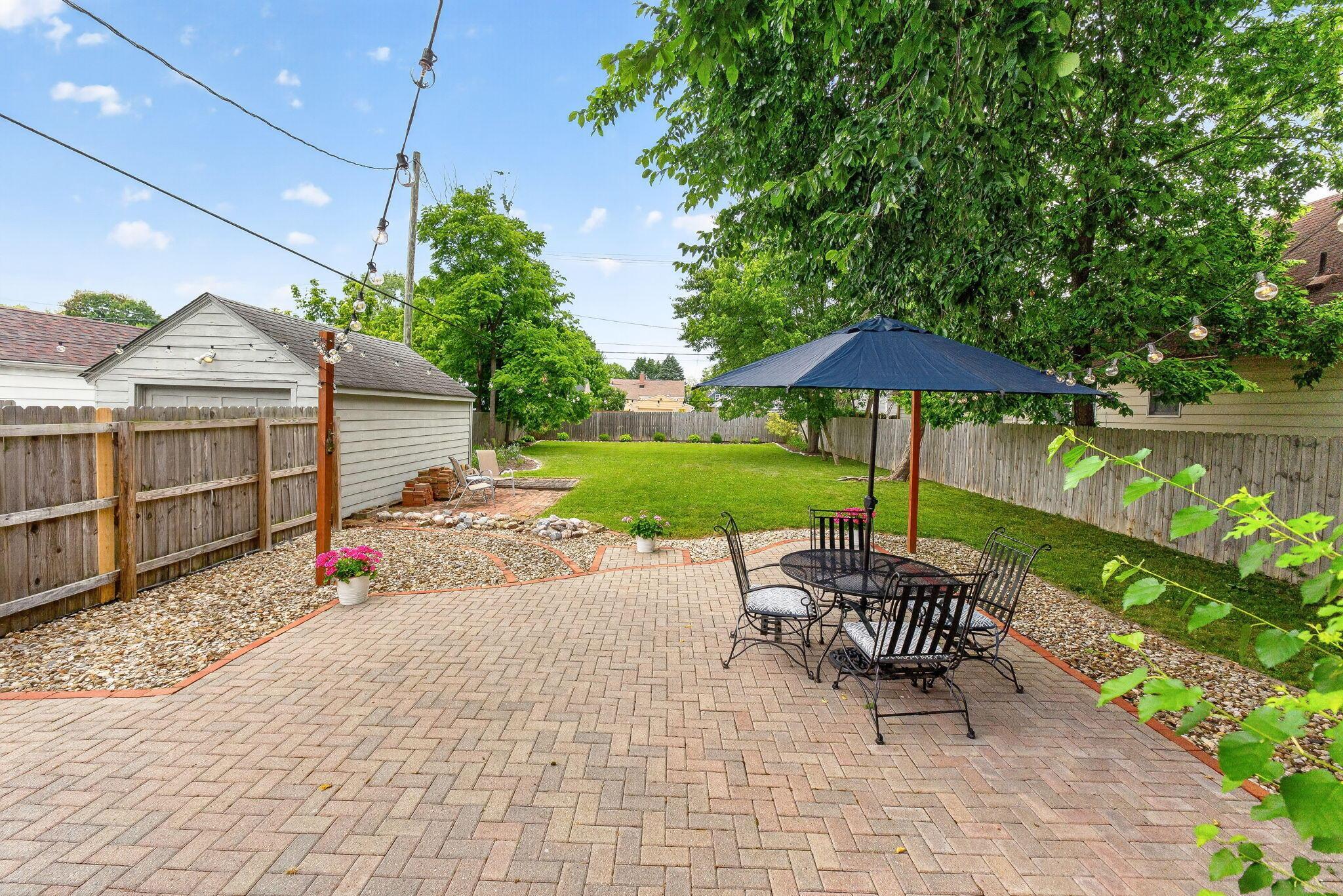 492 Wetmore Road Columbus, OH 43214 - Photo 42 of 55 Expansive backyard featuring a herringbone brick patio, mature trees, a manicured lawn, and a detached garage with siding