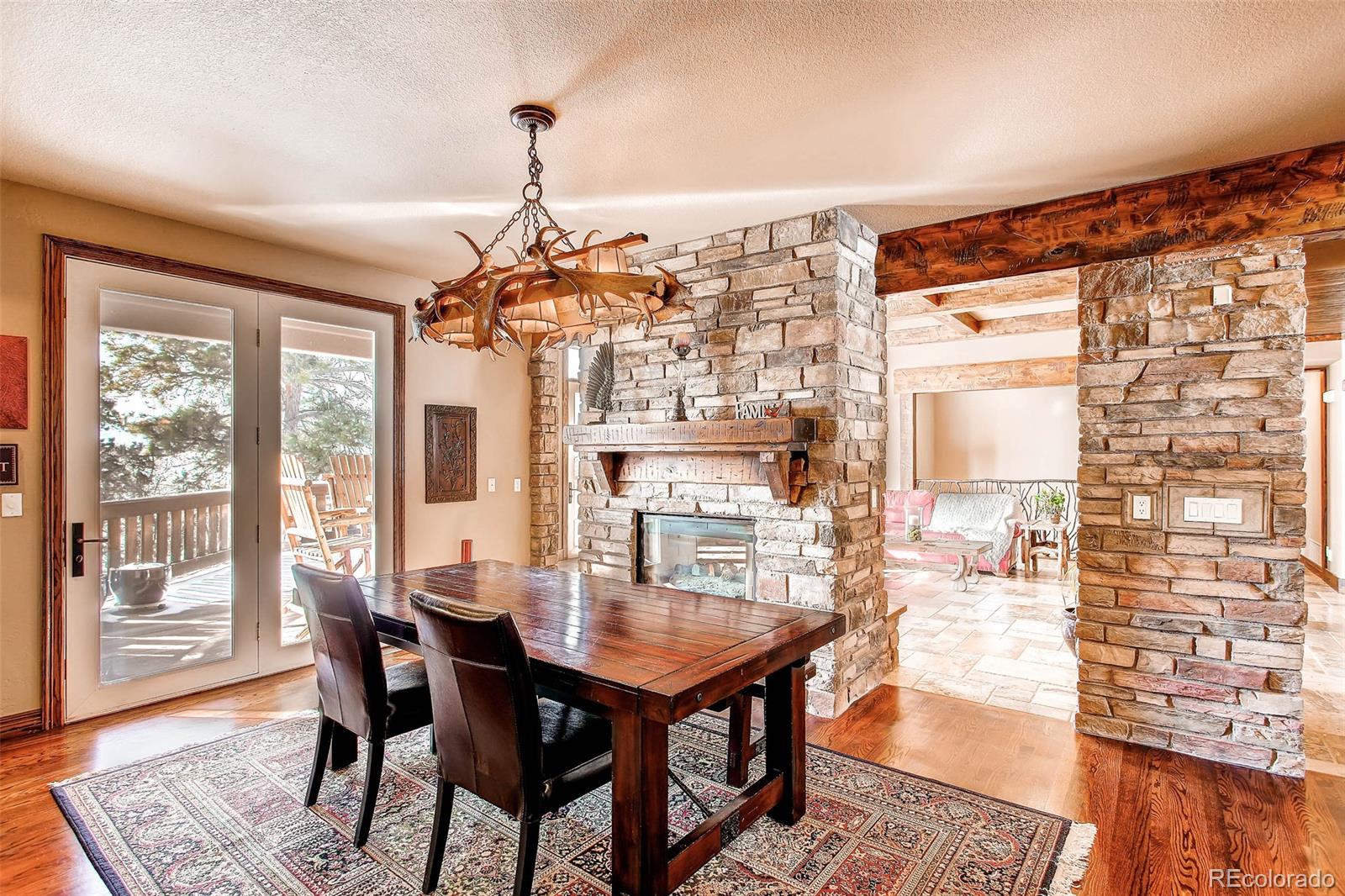 15241 Shadow Mountain Ranch Road Larkspur, CO 80118 - Photo 12 of 31 a dining room with furniture a chandelier and wooden floor