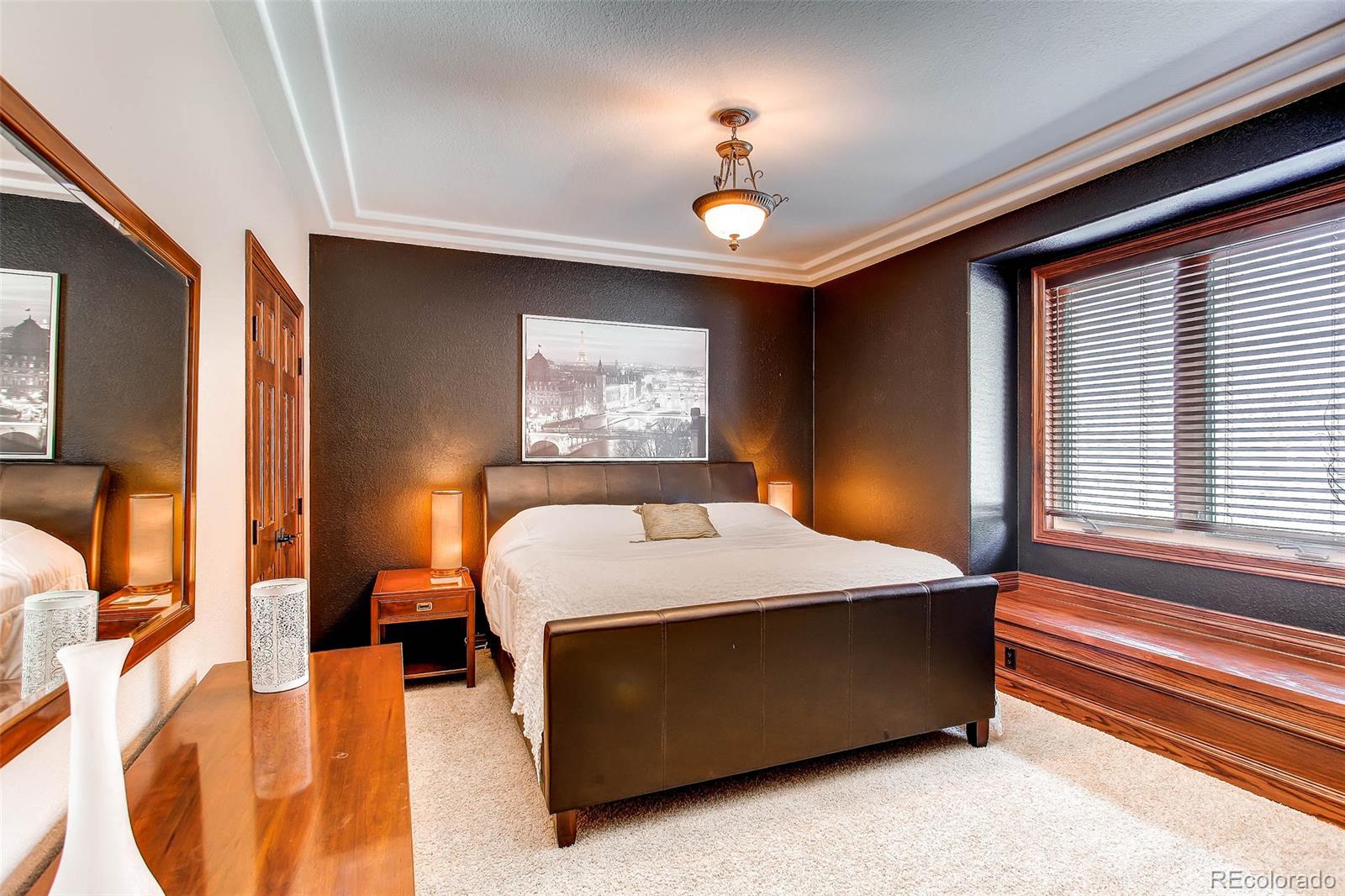15241 Shadow Mountain Ranch Road Larkspur, CO 80118 - Photo 17 of 31 a bedroom with a bed and a chandelier