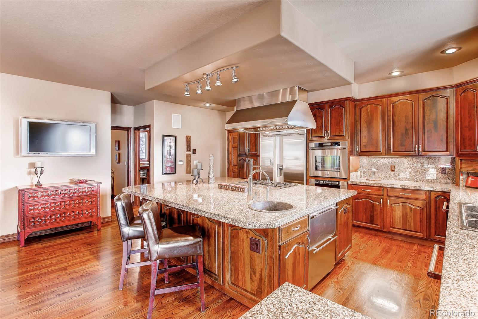 15241 Shadow Mountain Ranch Road Larkspur, CO 80118 - Photo 8 of 31 a kitchen with stainless steel appliances granite countertop a kitchen island a stove a sink a dining table and chairs