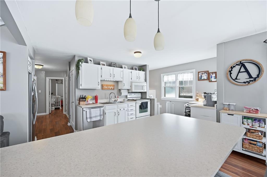 7376 Sharon-Mercer Road Mercer, PA 16137 - Photo 13 of 49 a large white kitchen with cabinets a stove a sink and a dining table with wooden floor