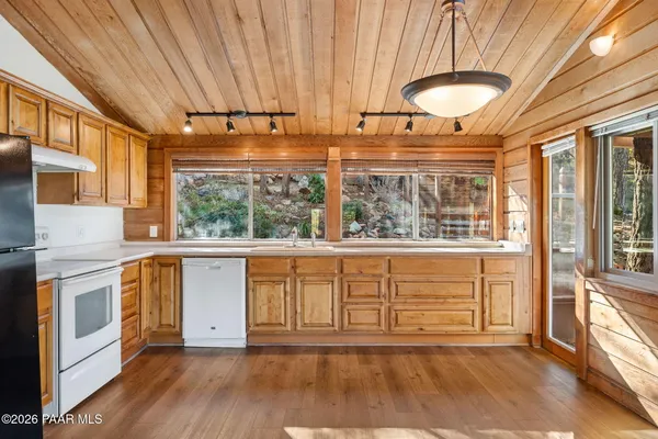 a view of open kitchen with granite countertop a stove top oven a sink with wooden cabinets and floor