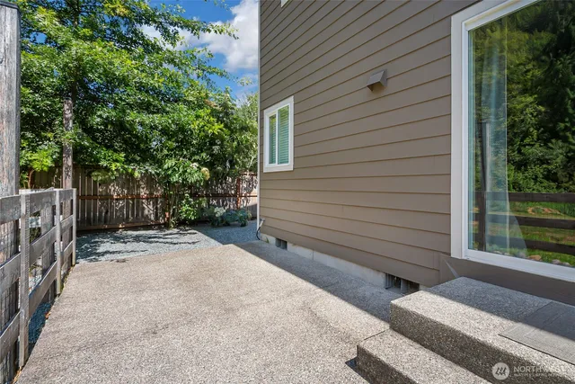 a backyard of a house with large trees and wooden fence