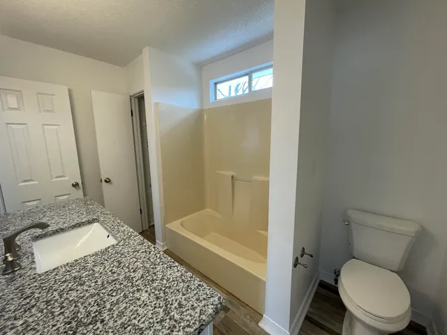 a bathroom with a granite countertop toilet and a shower