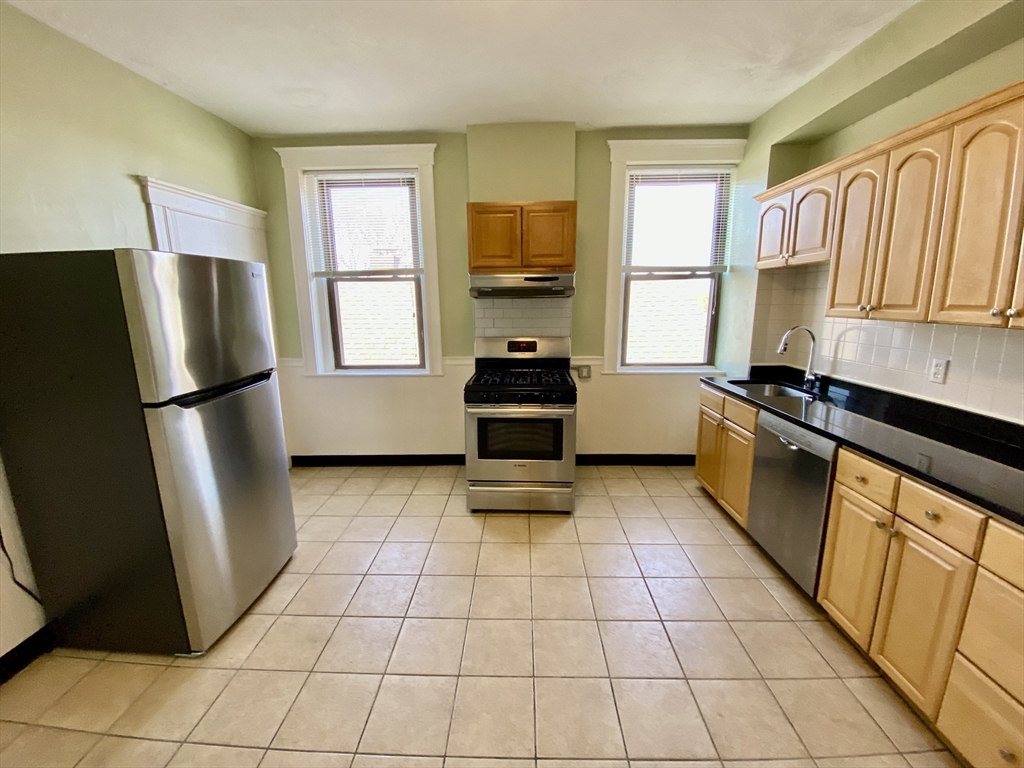 979 Chestnut Street, Unit 1 Newton, MA 02464 - Photo 2 of 6 a kitchen with a refrigerator a stove a sink and a window
