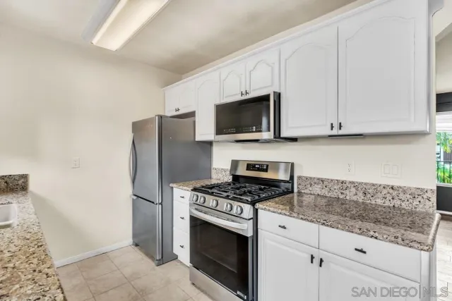 a kitchen with granite countertop a sink stove and refrigerator