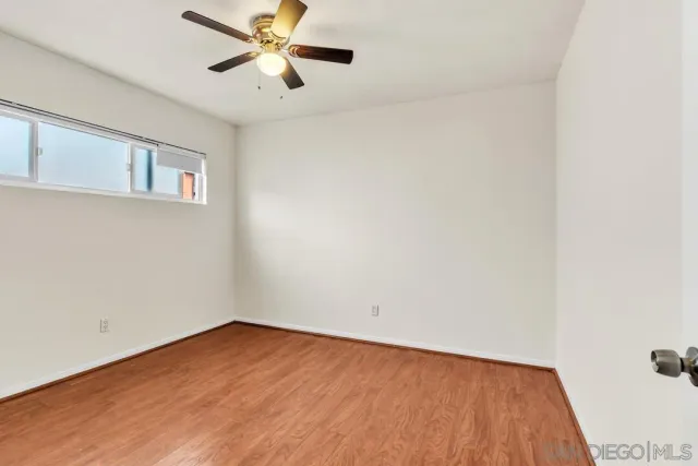 a view of an empty room with window and wooden floor