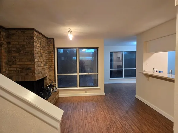 a view of an empty room with wooden floor and windows