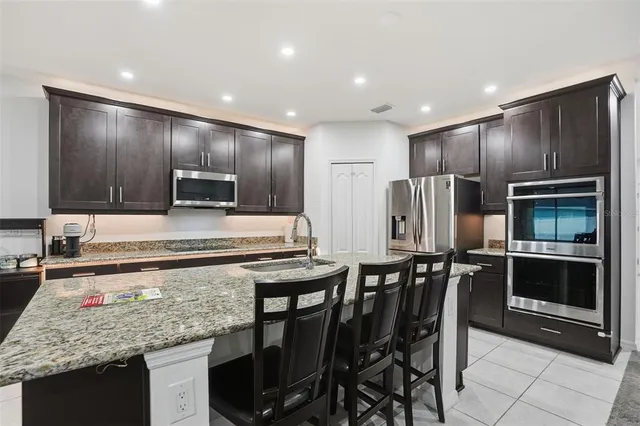 a kitchen with stainless steel appliances kitchen island granite countertop a table chairs microwave and refrigerator