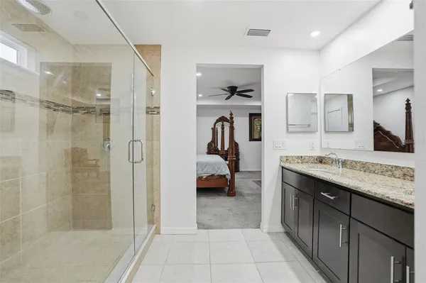 a bathroom with a granite countertop sink a mirror and shower