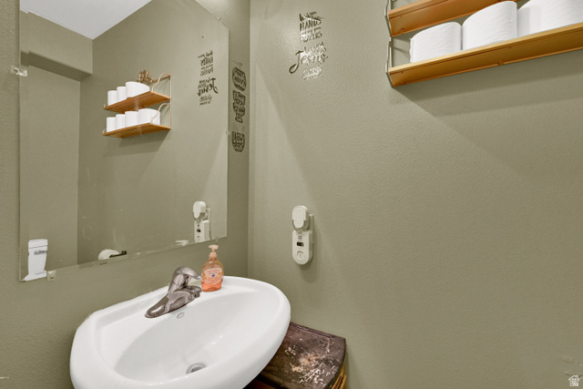 116 4th Street South Ogden, UT 84404 - Photo 7 of 7 Pedestal sink with chrome faucet, main level, mirror, and two-tier wood shelving