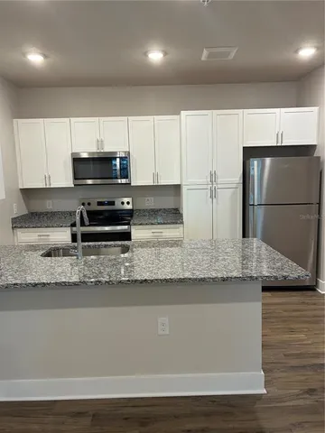 a kitchen with stainless steel appliances granite countertop a sink a stove a microwave a sink and a refrigerator