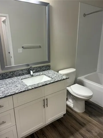 a bathroom with a granite countertop toilet sink and mirror