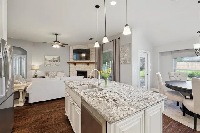 a large kitchen with kitchen island a stove a sink a center island and wooden floor