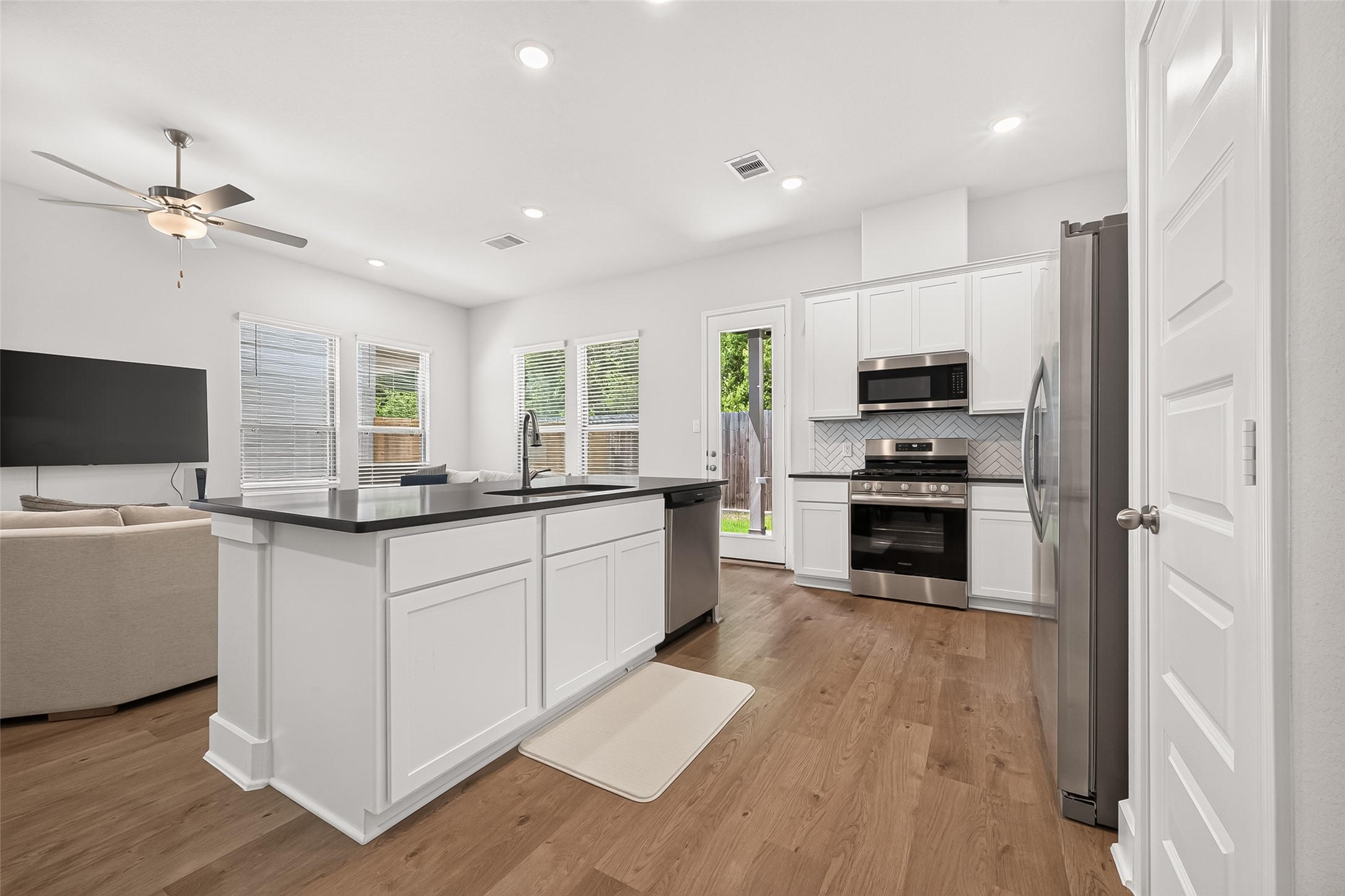 4004 Baja Lane Houston, TX 77045 - Photo 11 of 34 This beautifully appointed kitchen features high-end sterling silver appliances, pristine white cabinetry, and an oversized dark granite island that truly pops. Flooded with natural light from surrounding windows, the seamless view into the breakfast area and main family room creates a wonderfully bright and airy heart of the home.