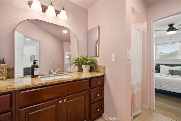 a en suite bathroom with a granite countertop sink and a mirror