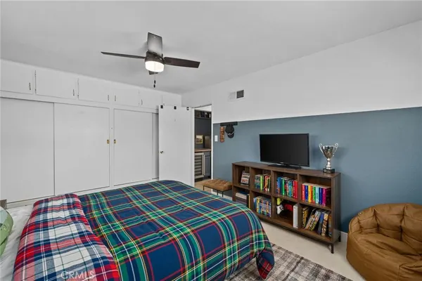 a bedroom with a bed a flat screen tv and a book shelf