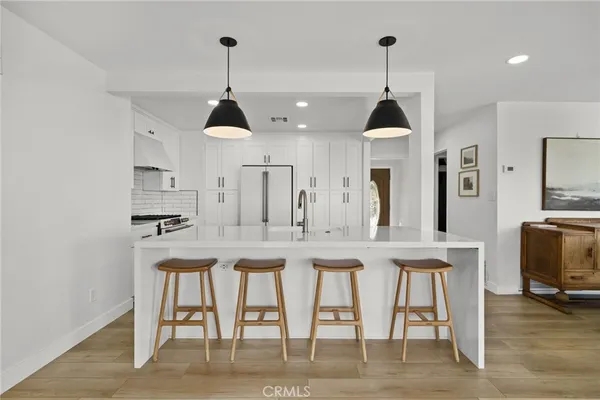 a kitchen with stainless steel appliances granite countertop a dining table chairs and white cabinets