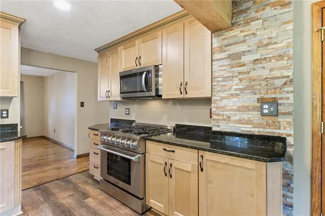 a kitchen with granite countertop a sink a stove and cabinets