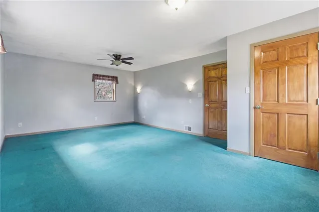 an empty room with a window and a ceiling fan