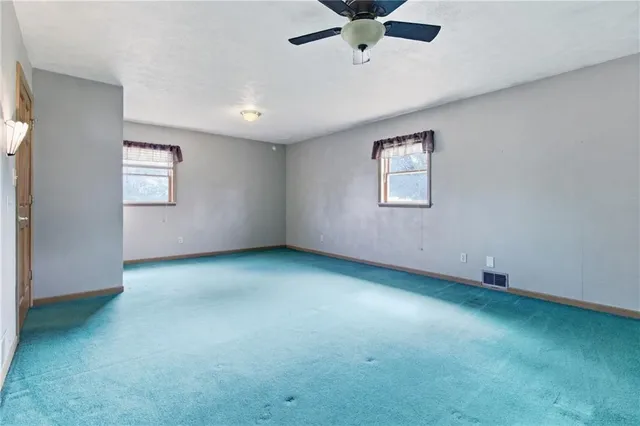 an empty room with a window and a ceiling fan