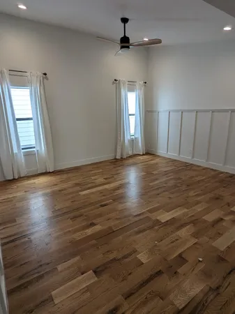 a view of an empty room with window and wooden floor