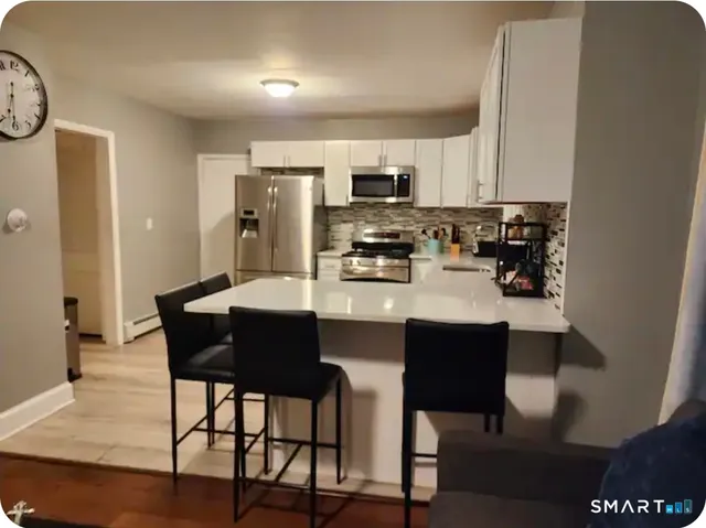 a kitchen with stainless steel appliances a dining table chairs and a refrigerator