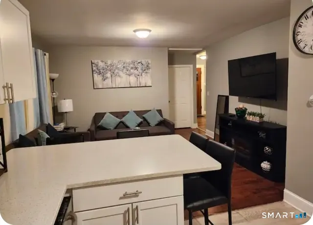 a living room with furniture a flat screen tv and kitchen view
