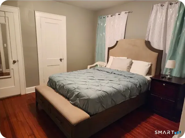 a bedroom with a bed wooden floor and a mirror
