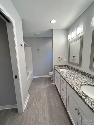 a bathroom with a granite countertop double vanity sink and a mirror