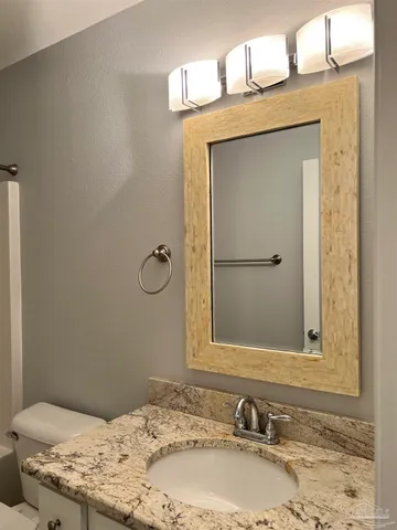 a bathroom with a granite countertop bathtub shower sink vanity and toilet