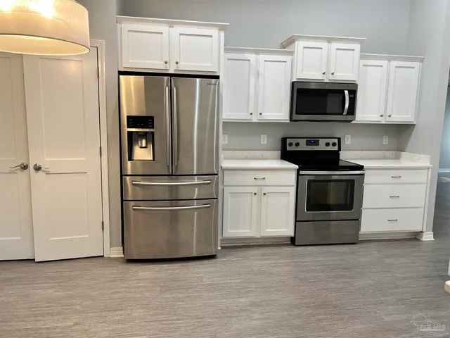 a kitchen with stainless steel appliances white cabinets and a refrigerator