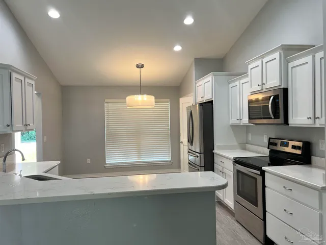 a kitchen with stainless steel appliances granite countertop a refrigerator a stove a sink and a microwave