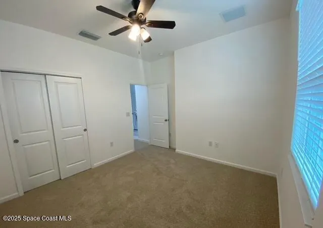 an empty room with a window and a fan