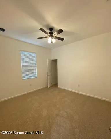 an empty room with a ceiling fan and a window