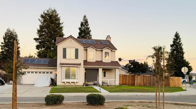 a front view of a house with a garden and trees