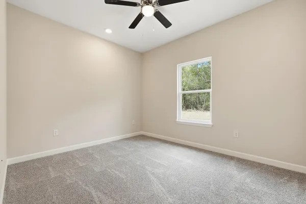 an empty room with a window and a ceiling fan