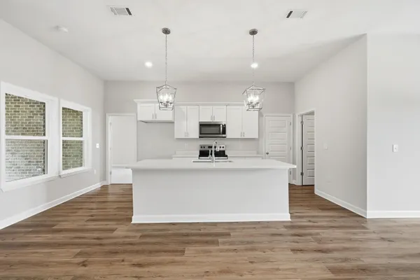 a view of large kitchen with granite countertop stainless steel appliances sink and refrigerator