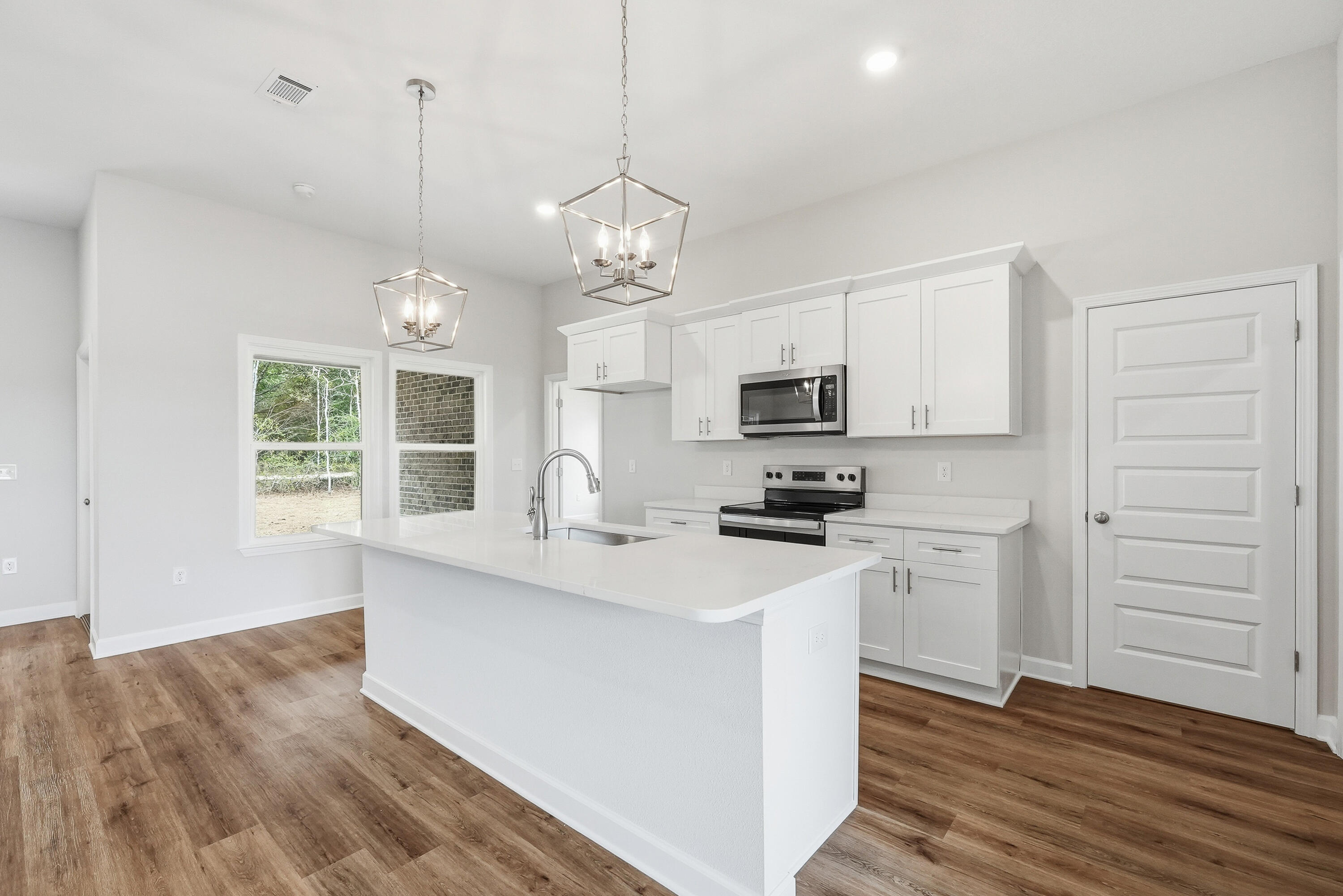6105 Mildreds Way Crestview, FL 32539 - Photo 9 of 28 a kitchen with stainless steel appliances granite countertop a sink a stove a refrigerator and white cabinets with wooden floor