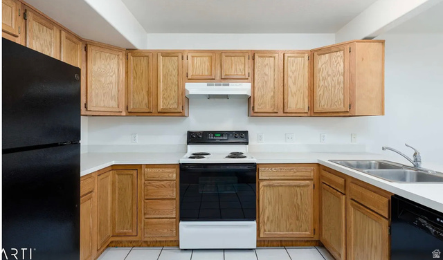 4823 Old Post Road Ogden, UT 84403 - Photo 8 of 19 U-shaped kitchen featuring wood cabinetry, white countertops, white tile flooring, a black refrigerator, and a black and white electric range