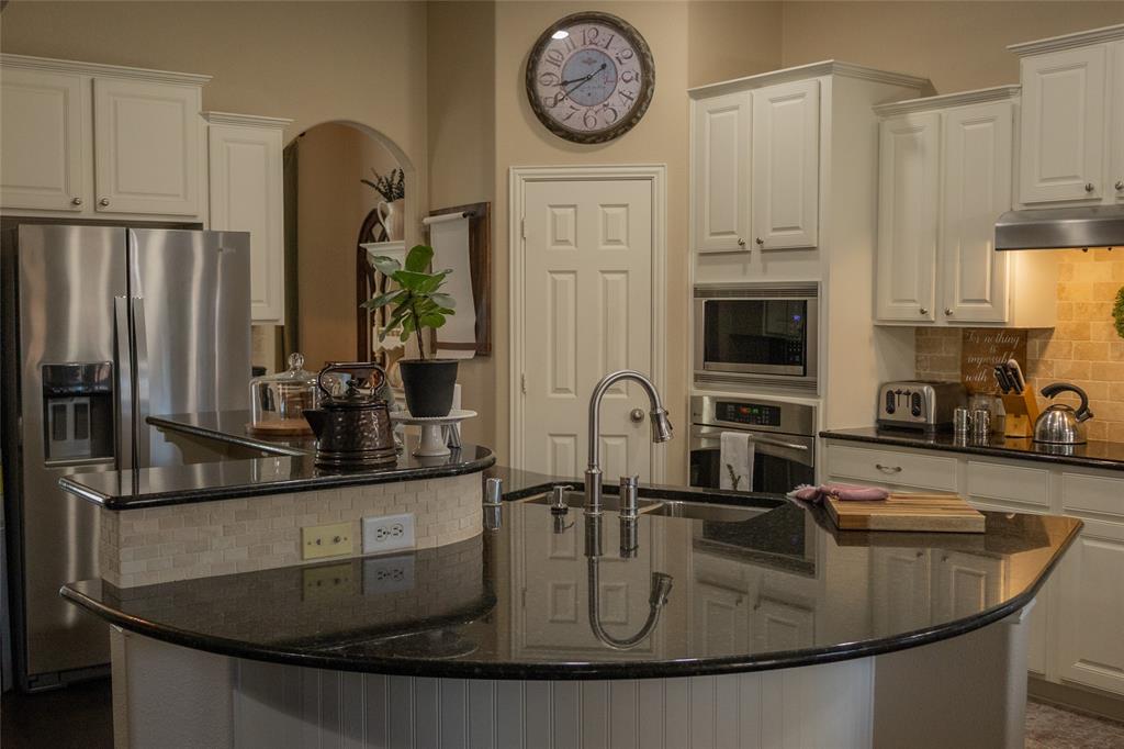 1395 Southern Rockwall, TX 75087 - Photo 7 of 22 a kitchen with kitchen island granite countertop a sink a stove and cabinets