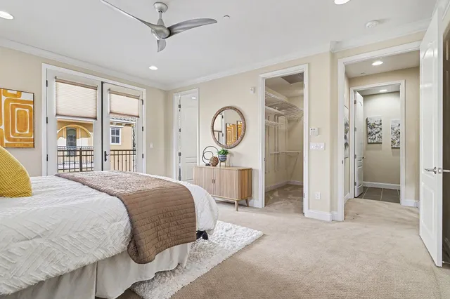 a bedroom with a bed large mirror and a large window