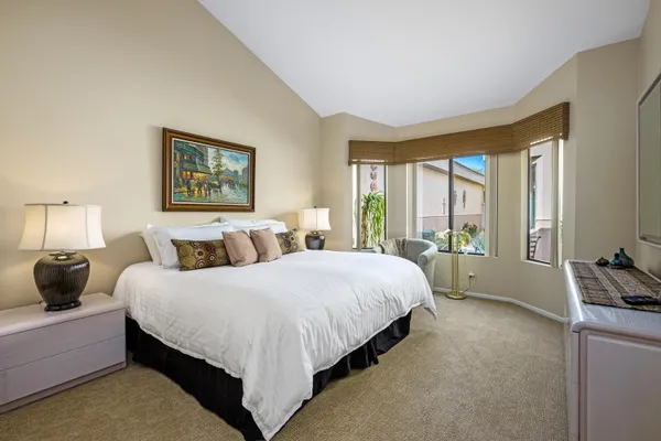 a spacious bedroom with a large bed and a flat tv screen on dresser