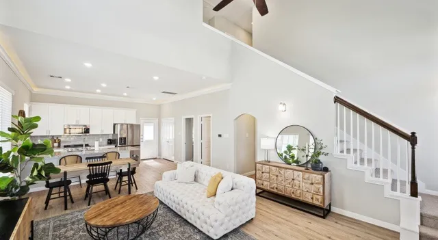 a living room with furniture kitchen view and a wooden floor