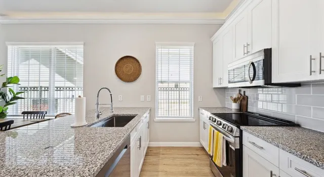 a kitchen with granite countertop a sink a stove and cabinets