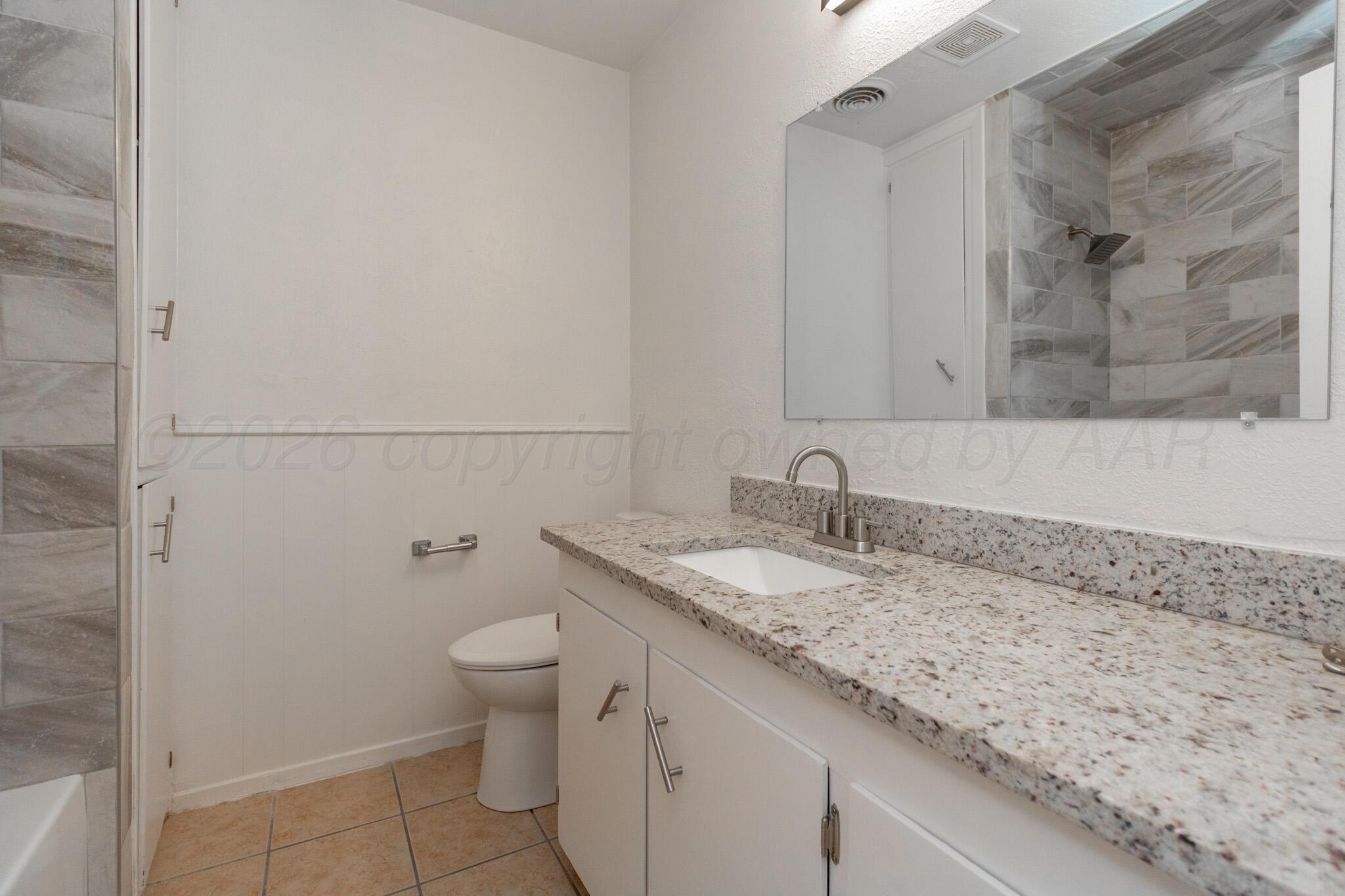4216 Southwest 38th Avenue Amarillo, TX 79109 - Photo 13 of 19 a bathroom with a granite countertop sink a toilet and a mirror